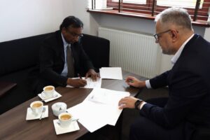 Rektor PANS w Głogowie, dr Jarosław Hermaszewski oraz Prezes American Medical Academy – John K. Eapen. Panowie w garniturach, w gabinecie, przy stole podpisują list intencyjny o współpracy pomiędzy instytucjami.