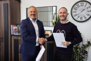 Rektor PANS w Głogowie: dr Jarosław Hermaszewski i przedstawiciel Pulse of Mind: Mindaugas Latisenka podają sobie dłonie w Biurze Rektora. W drugich dłoniach trzymają teczki z dokumentami.