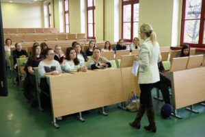 Uczestnicy spotkania Erasmus+ słuchają prelegentki w sali wykładowej uczelni.