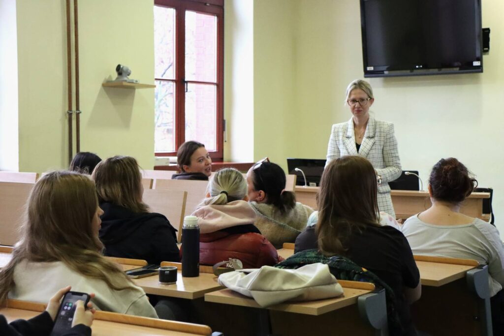 Uczestnicy spotkania Erasmus+ słuchają prelegentki w sali wykładowej uczelni.