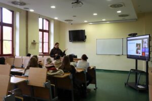 Uczestnicy spotkania Erasmus+ słuchają prelegentki w sali wykładowej uczelni.