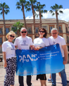 Pracownicy PANS w Głogowie z flagą uczelni podczas mobilności Erasmus+ w Maladze